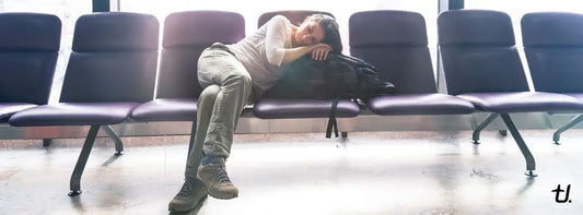 Tired traveller sleeping across airport seats while waiting for a long-haul flight
