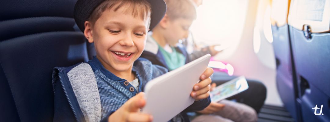 Children travelling on a plane, with a young boy using a tablet for entertainment
