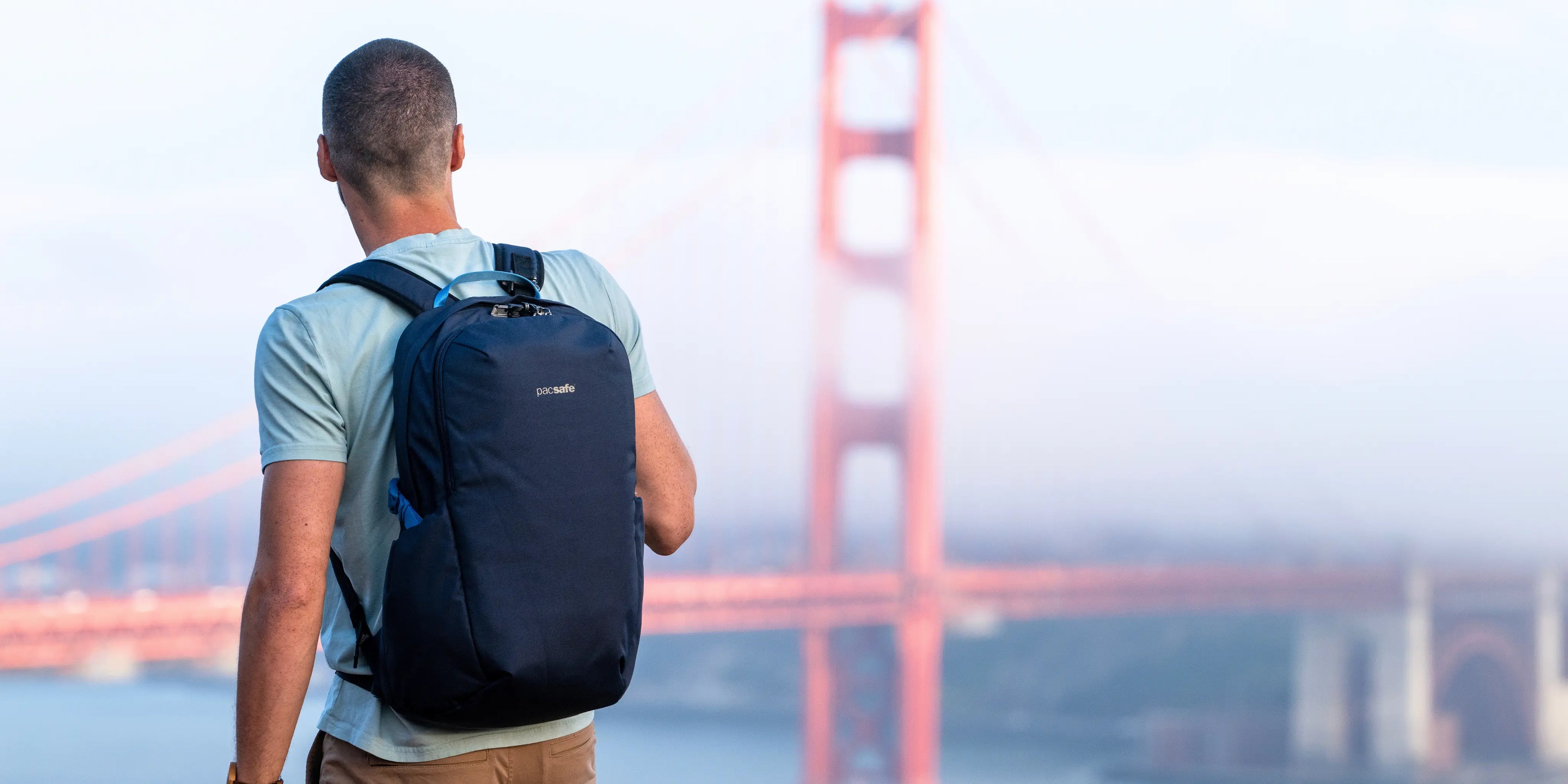 Man with a Pacsafe V Tour 26L Anti-Theft 16" Laptop Backpack standing in front of the Golden Gate Bridge