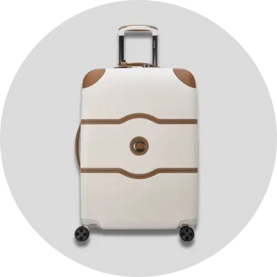 Cream-colored hard-shell suitcase with brown accent stripes and corner protectors, featuring a retractable handle and four spinner wheels.