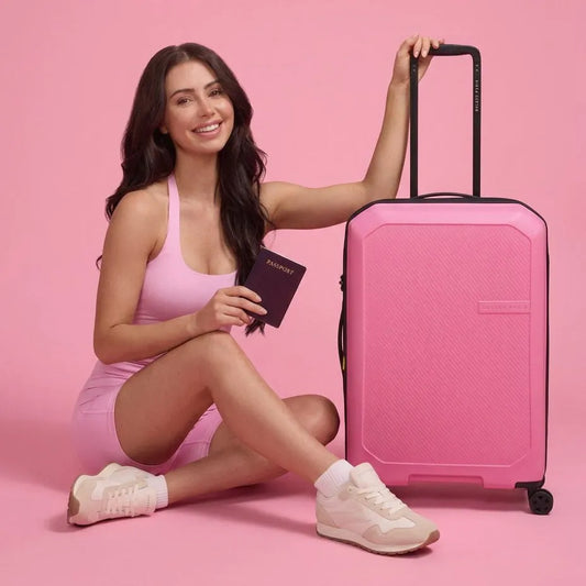 girl sits next to a Delsey Anvers 75 cm 4 Wheel Expandable Suitcase - Pink