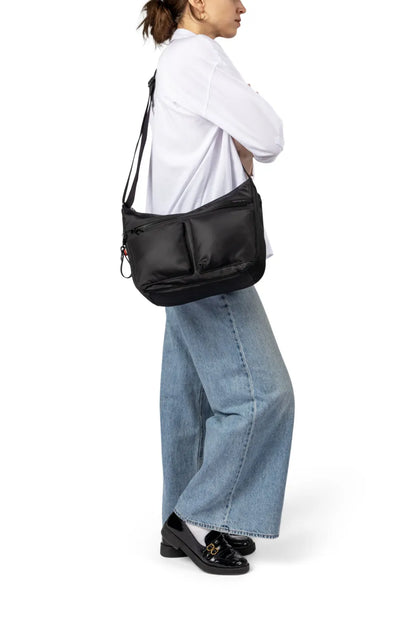 Hedgren ALEX NEO Large Crossbody Bag with RFID in Black, worn crossbody at the hip by a woman in a white shirt and wide leg jeans