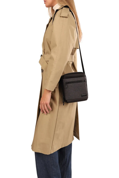 Hedgren APP Men's Vertical Crossover 7" Tablet Pouch with RFID in Black, worn crossbody at the hip by a woman in a trench coat