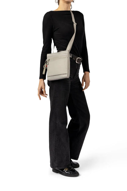 Hedgren LEONCE Small Vertical Crossbody Bag with RFID in Black, worn crossbody at the hip by a woman in a black top and dark jeans