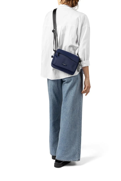 Hedgren NEUTRON Medium Crossbody Bag in Green Milieu, worn crossbody at the back by a woman in a white shirt and jeans, seen from behind