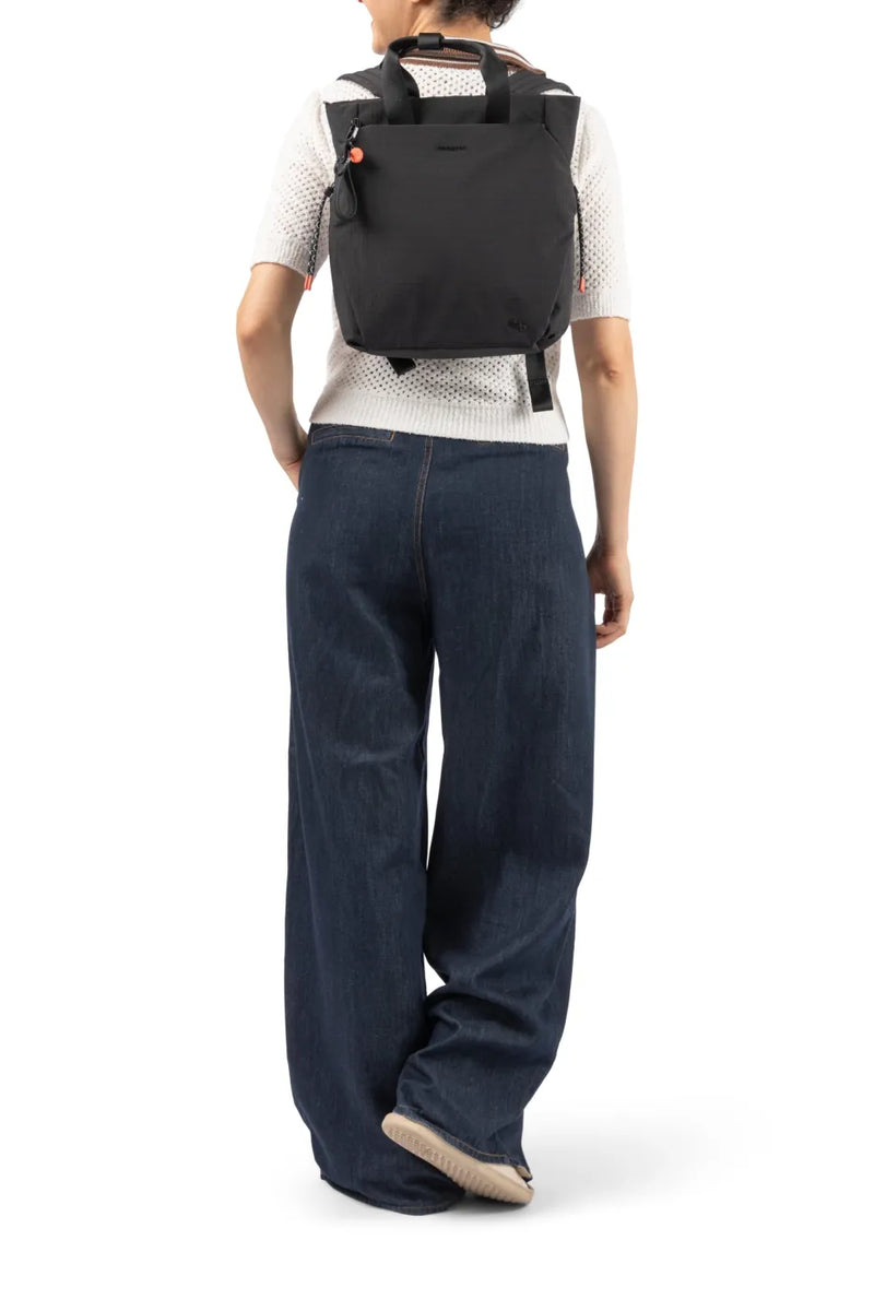 Hedgren NORIO Small Backpack in Black, worn on both shoulders over a white knit and wide jeans, seen from behind