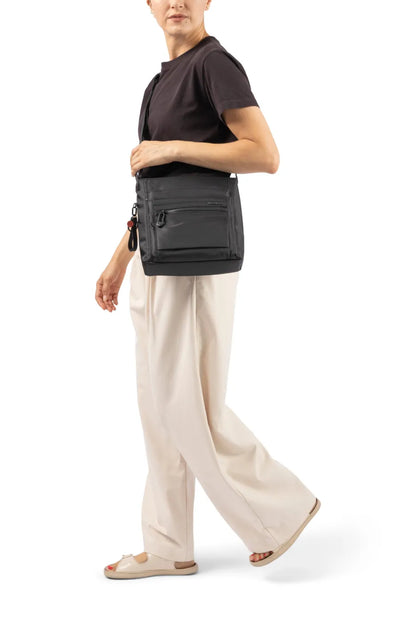 Hedgren ORVA Crossbody Bag with RFID Pocket in Black, worn crossbody at the waist by a woman in a dark tee and cream trousers
