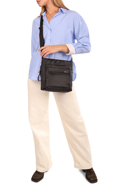 Hedgren ORVA NEO Crossbody Bag with RFID Pocket in Print SS26, worn crossbody at the hip by a woman in a blue shirt and cream trousers