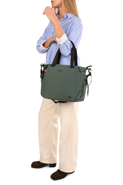 Hedgren SATOSHI 14" Laptop Tote in Black, carried by its top handles at the side of a woman in a blue shirt