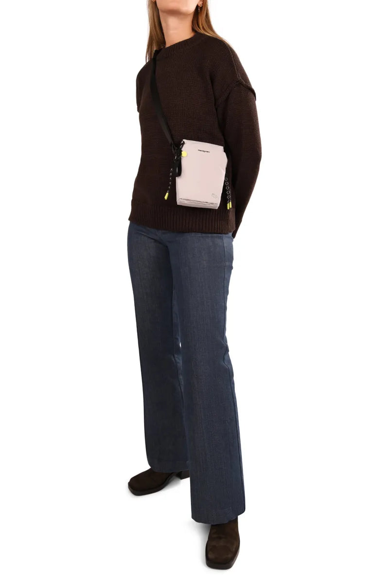 Hedgren SIPHO Phone/Bottle Bag in Vulcan Blue, worn crossbody at the chest by a woman in a brown knit and jeans