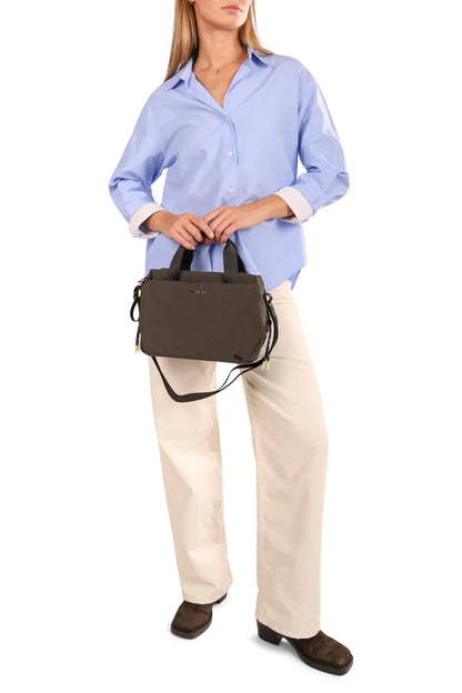 Hedgren TOMOKO Handbag in Orchid Ice, carried by its top handles in front of a woman in a blue shirt