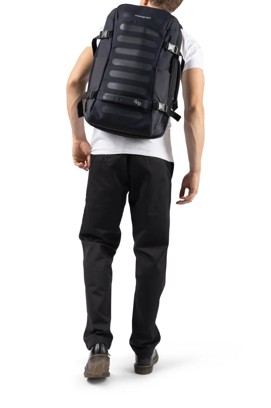 Hedgren TRIP L Expandable 15.6" Laptop Travel Backpack with RFID in Black, worn on both shoulders by a man in a white tee, seen from behind