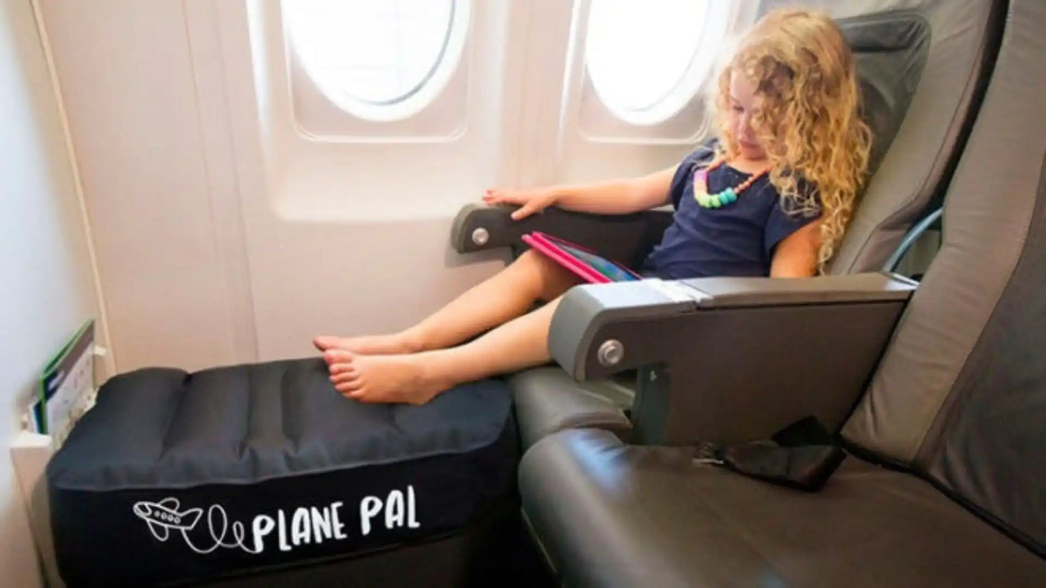 An inflatable black footrest designed for airplane travel, providing a comfortable space for a child to extend their legs.