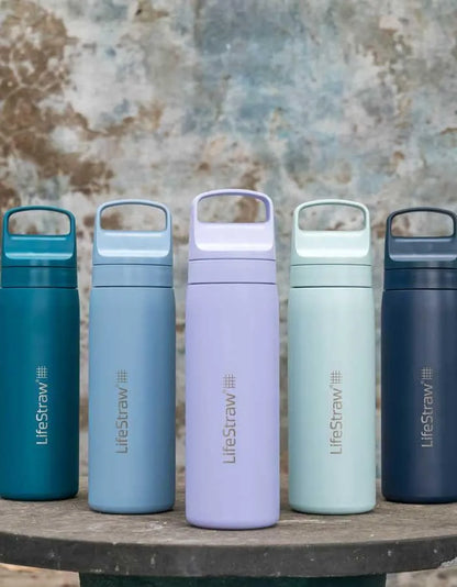 LifeStraw Go 2.0: five LifeStraw Go 500ml stainless steel bottles in different colours lined up on a weathered stone table