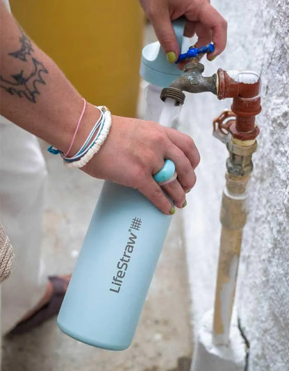 LifeStraw Go 2.0: a light blue LifeStraw Go 500ml stainless steel bottle being filled from an outdoor garden tap