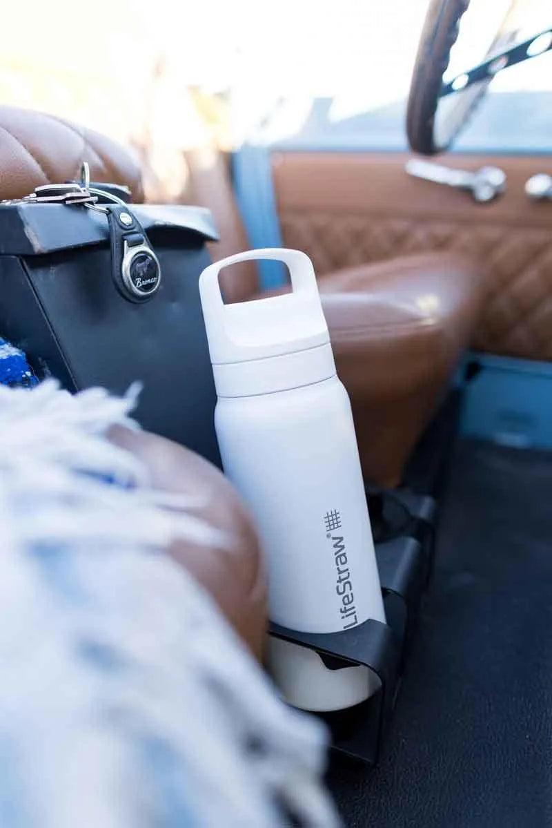 LifeStraw Go 2.0: a white stainless steel LifeStraw Go bottle tucked into a bag on the leather seat of a vintage car