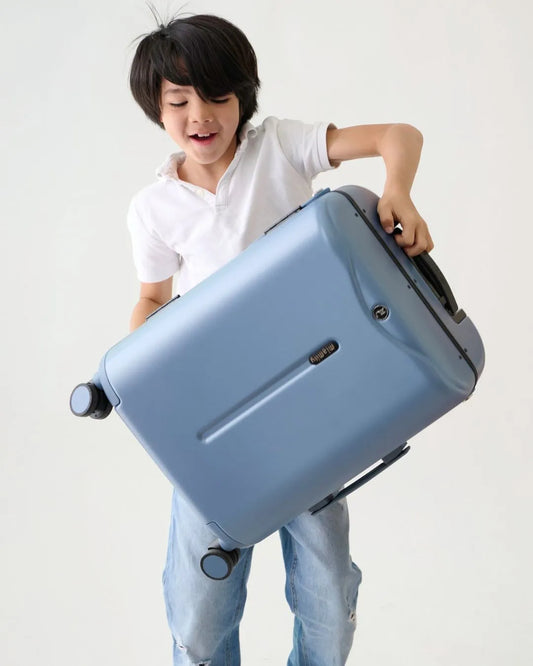 Child holding a MiaMily 48 cm Ride-On Carry-on Suitcase - Slate Blue