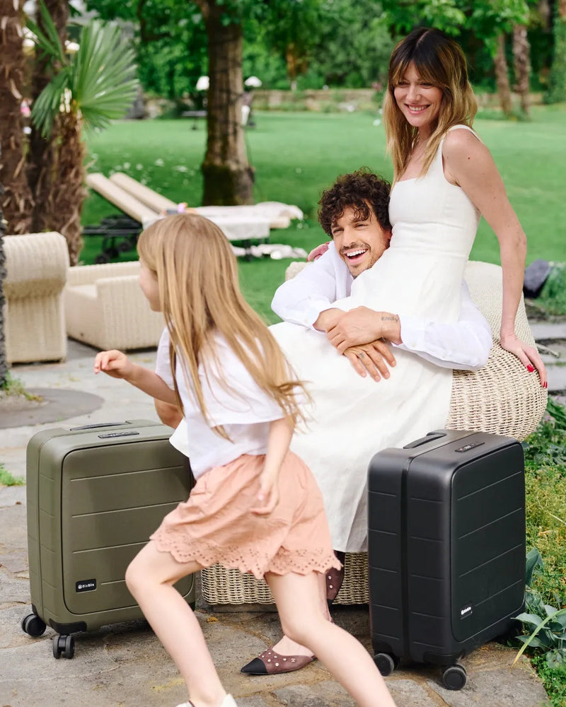 Family in the garden with MiaMily Carry-on Seat Pro suitcases in Olive and Black