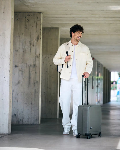 Traveller walking with the MiaMily Carry-on Seat Pro suitcase in Olive