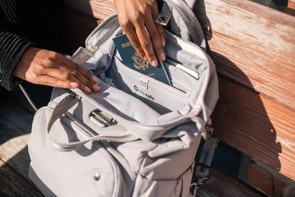 Pacsafe Citysafe CX Anti-Theft 16" Laptop Backpack in Gravity Grey, a passport being lifted from the pocket inside the open bag