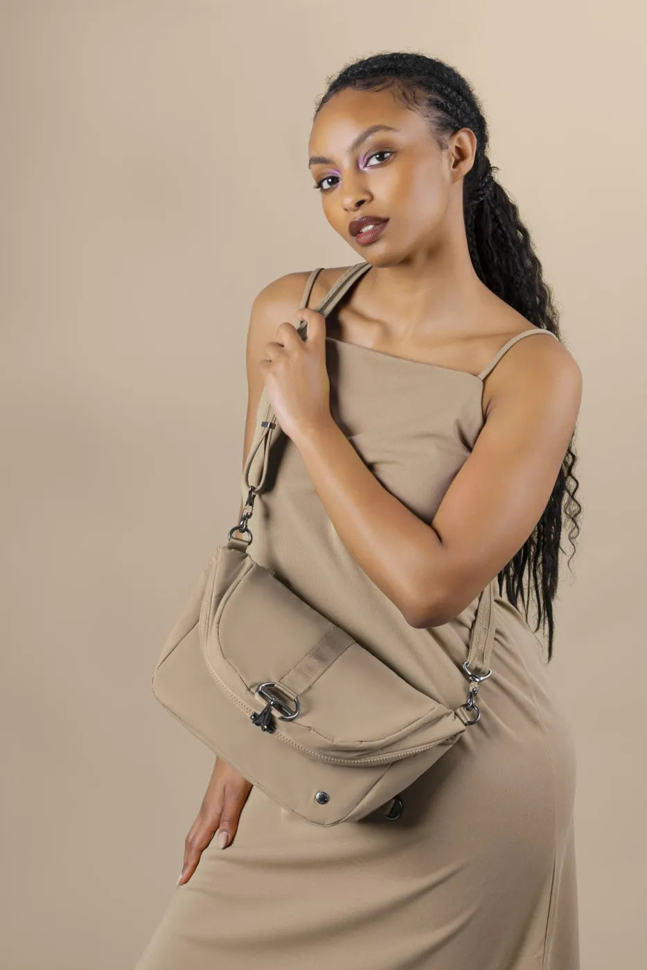 Pacsafe Citysafe CX Anti-Theft Convertible Backpack / Shoulder Bag in Taupe, worn as a shoulder bag by a woman in a slip dress