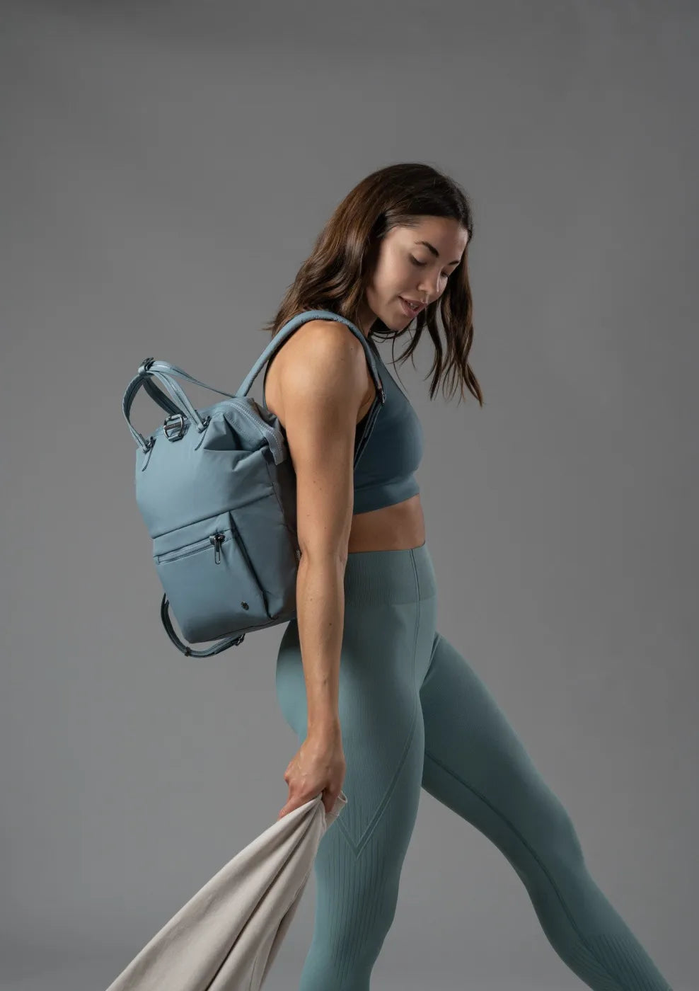 Pacsafe Citysafe CX Econyl Anti-Theft Mini Backpack in Fresh Mint, worn on both shoulders by a woman walking, seen from the side
