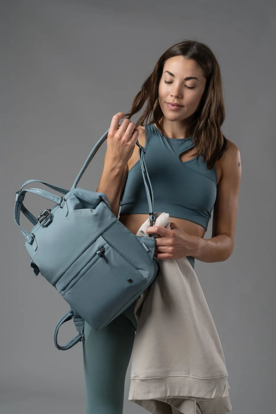 Pacsafe Citysafe CX Econyl Anti-Theft Mini Backpack in Fresh Mint, held by its top handles while a sweatshirt is packed inside