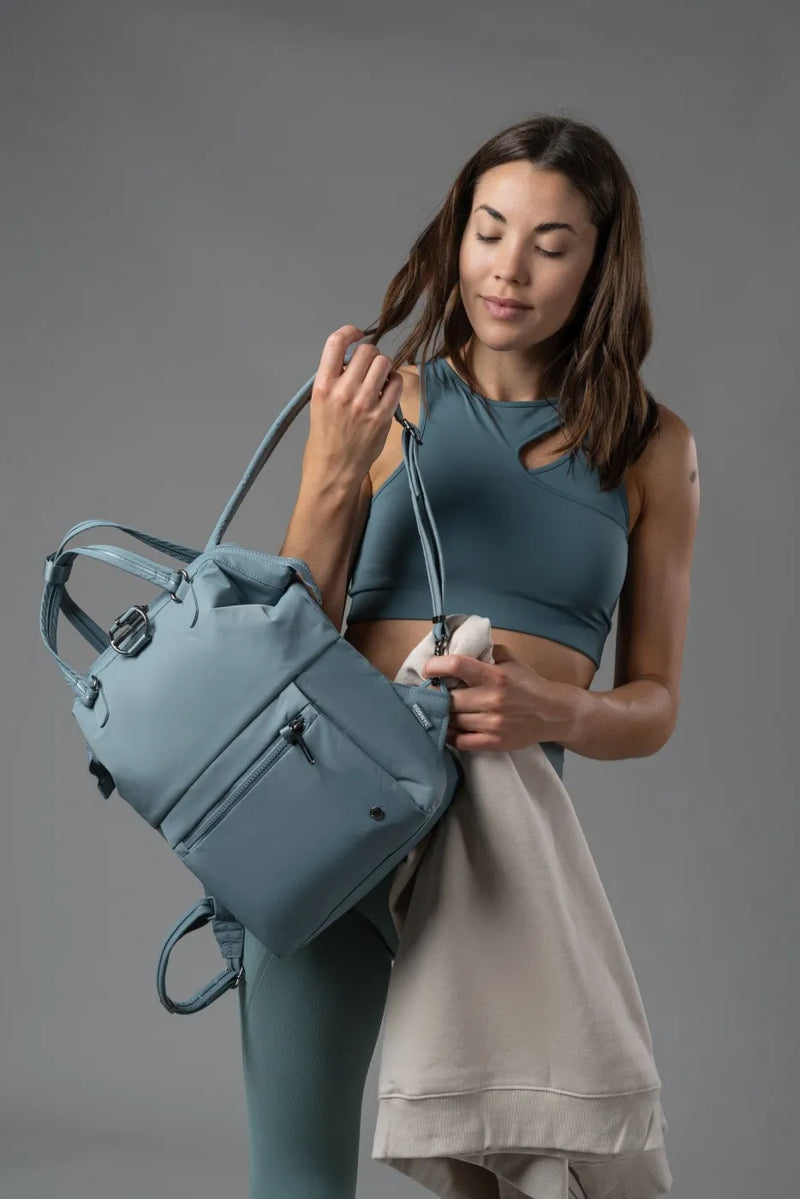 Pacsafe Citysafe CX Econyl Anti-Theft Mini Backpack in Fresh Mint, held by its top handles while a sweatshirt is packed inside
