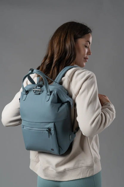 Pacsafe Citysafe CX Econyl Anti-Theft Mini Backpack in Fresh Mint, worn on both shoulders over a cream sweatshirt, seen from behind