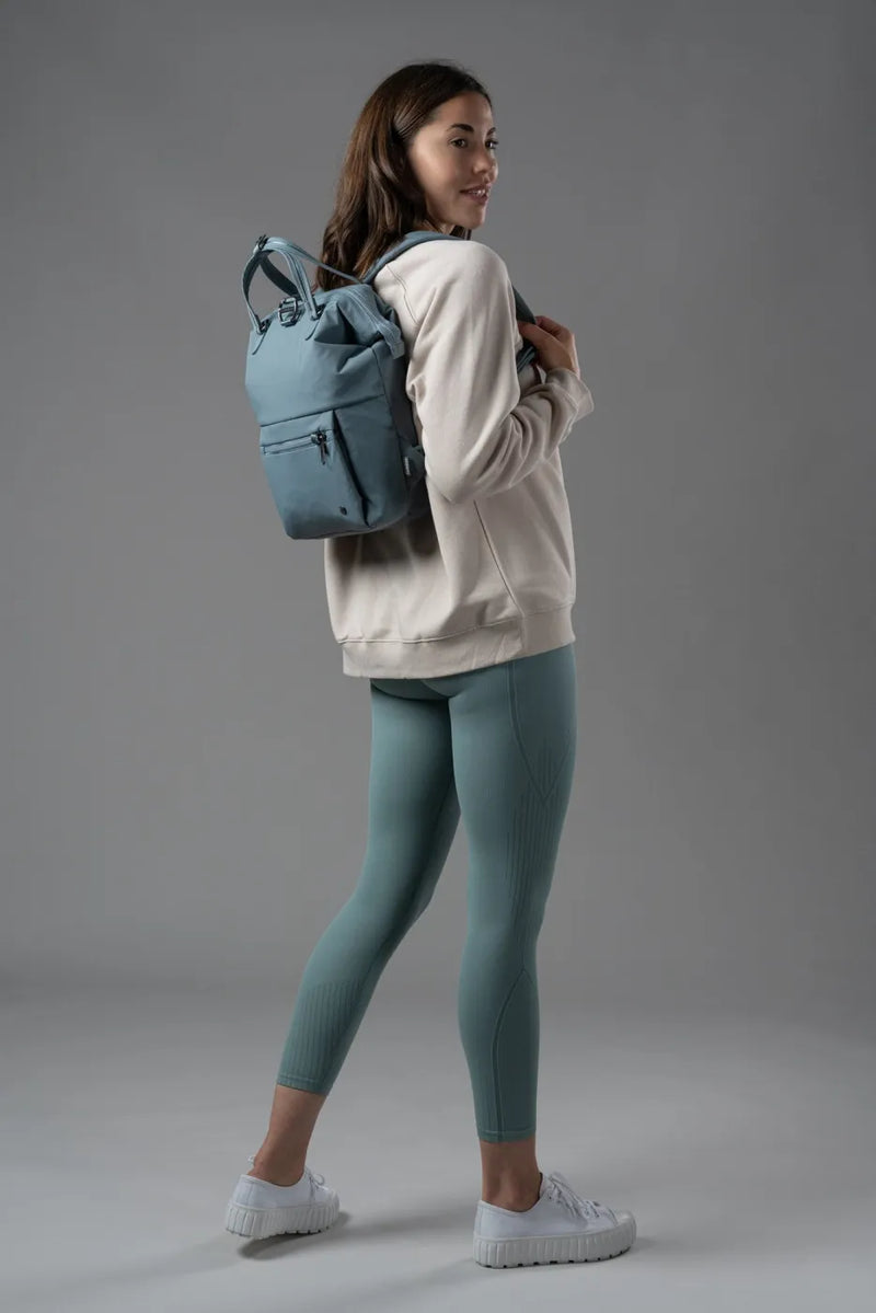Pacsafe Citysafe CX Econyl Anti-Theft Mini Backpack in Fresh Mint, worn on both shoulders by a woman looking back over her shoulder