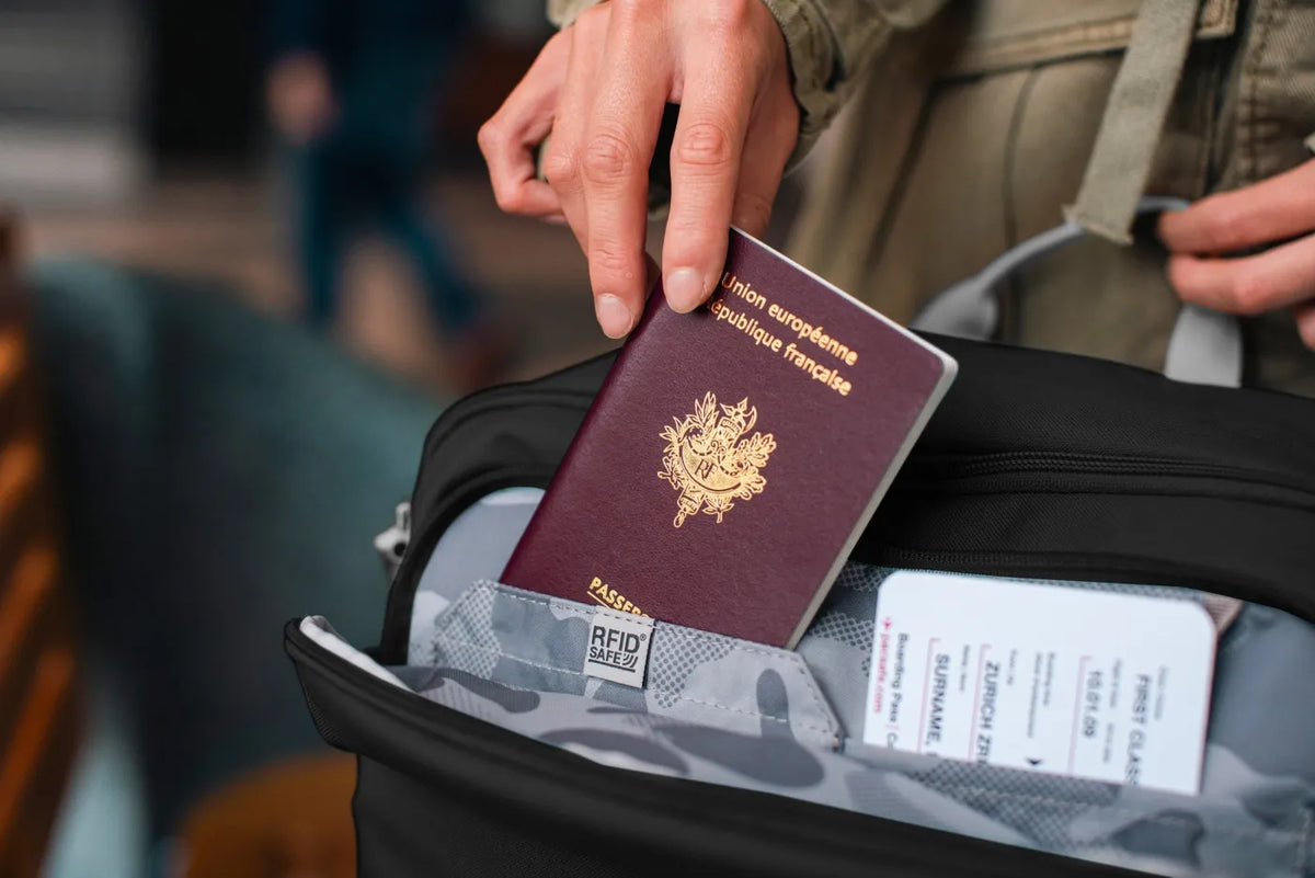 Pacsafe GO 34L Anti-Theft Carry-on Backpack in Jet Black, a passport being lifted from the front pocket beside a boarding pass