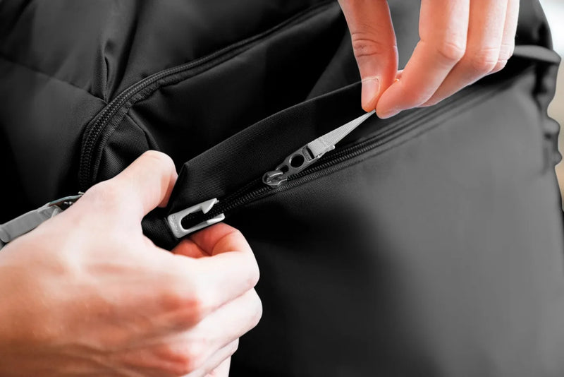 Pacsafe GO 44L Anti-Theft Carry-on Backpack in Jet Black, the lockable zip being opened by hand