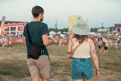 Pacsafe Go Anti-theft Festival Crossbody Bag in Jet Black, worn crossbody by a man standing with a friend at a festival