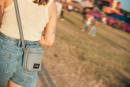 Pacsafe Go Anti-theft Micro Crossbody Bag in Fresh Mint, worn crossbody at the hip by a woman walking a festival field