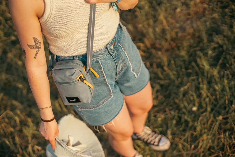 Pacsafe Go Anti-theft Micro Crossbody Bag in Fresh Mint, worn at the hip over denim shorts, seen from above