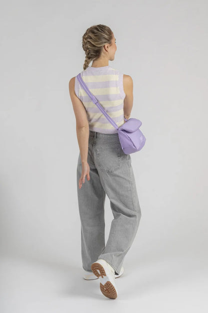 Pacsafe Go Anti-Theft Saddle Crossbody Bag in Lavender, worn crossbody at the back of a woman in grey jeans, seen from behind