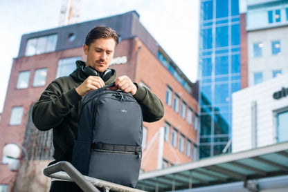 Pacsafe Metrosafe X Anti-Theft 25L 16" Laptop Backpack in Slate, opened at the top by a man standing on a city street