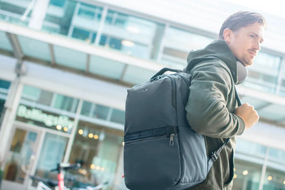 Pacsafe Metrosafe X Anti-Theft 25L 16" Laptop Backpack in Slate, worn on both shoulders by a man walking past a shopfront