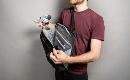 Pacsafe Metrosafe X Commuter Anti-Theft 16" Laptop Backpack in Black, held open by a man taking out a camera