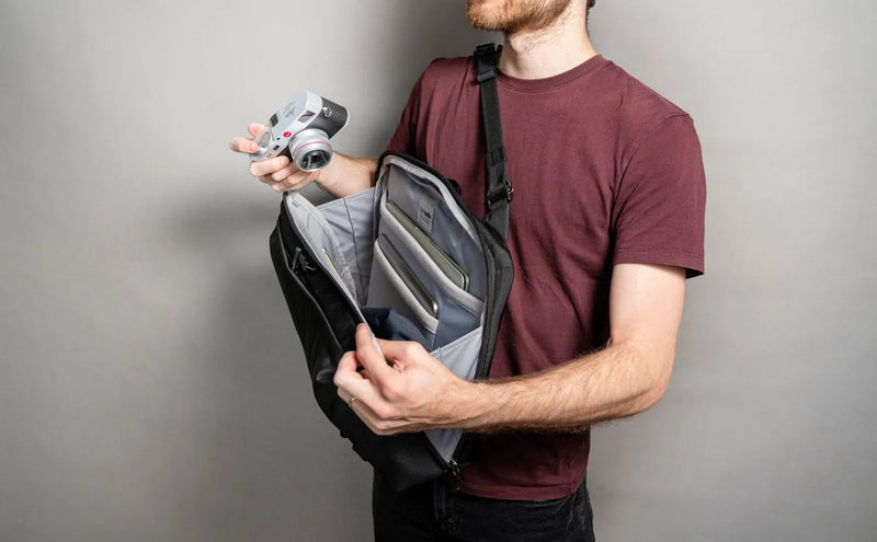Pacsafe Metrosafe X Commuter Anti-Theft 16" Laptop Backpack in Black, held open by a man taking out a camera