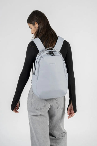 Pacsafe V All-Around 16L Anti-Theft 13" Laptop Backpack in Digital Grey, worn on both shoulders by a woman in a black top, seen from behind