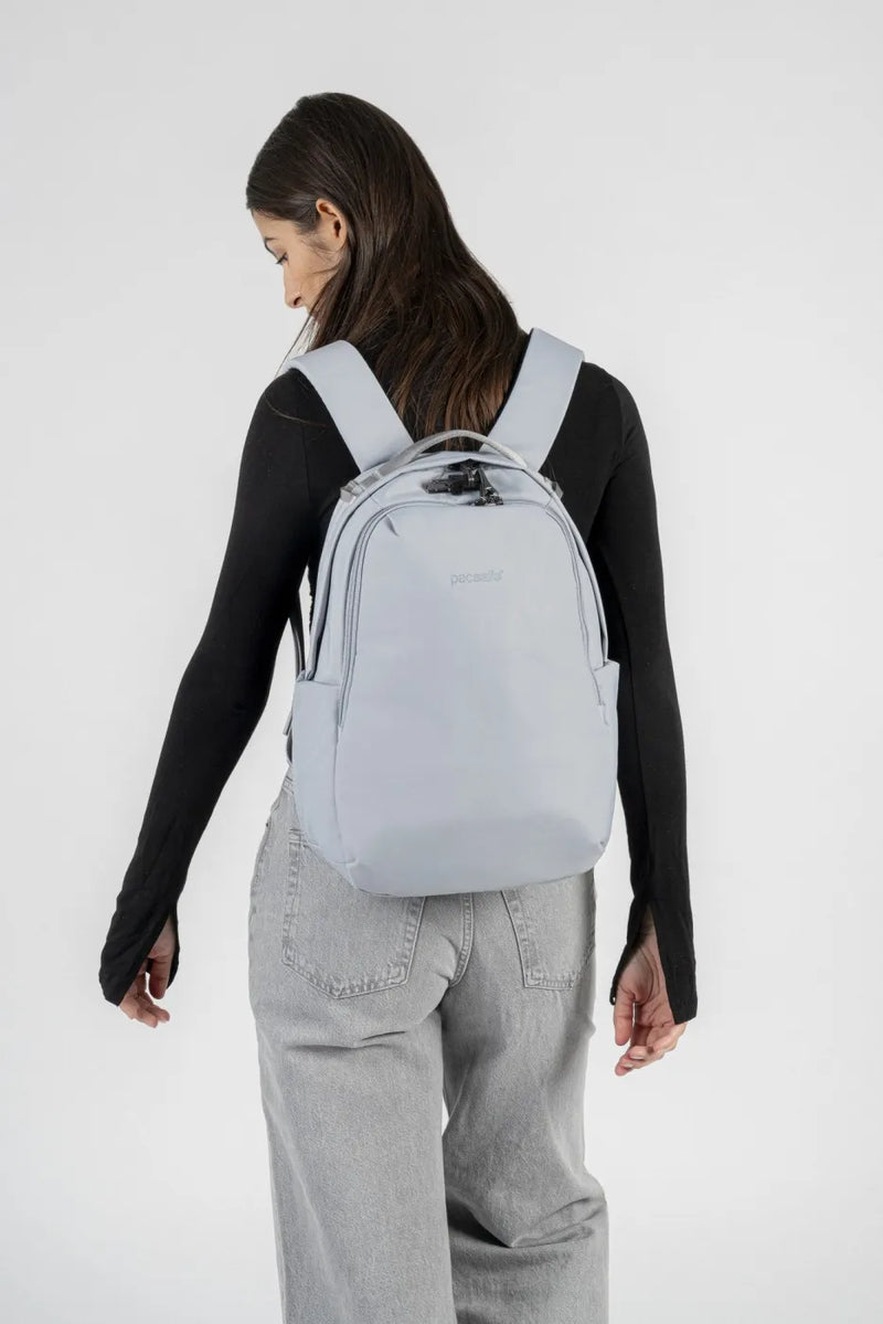 Pacsafe V All-Around 16L Anti-Theft 13" Laptop Backpack in Digital Grey, worn on both shoulders by a woman in a black top, seen from behind
