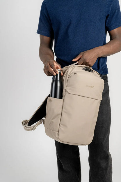 Pacsafe V City 20L Anti-Theft 16" Laptop Backpack in Beige, held at the side while a man slides a water bottle into the side pocket