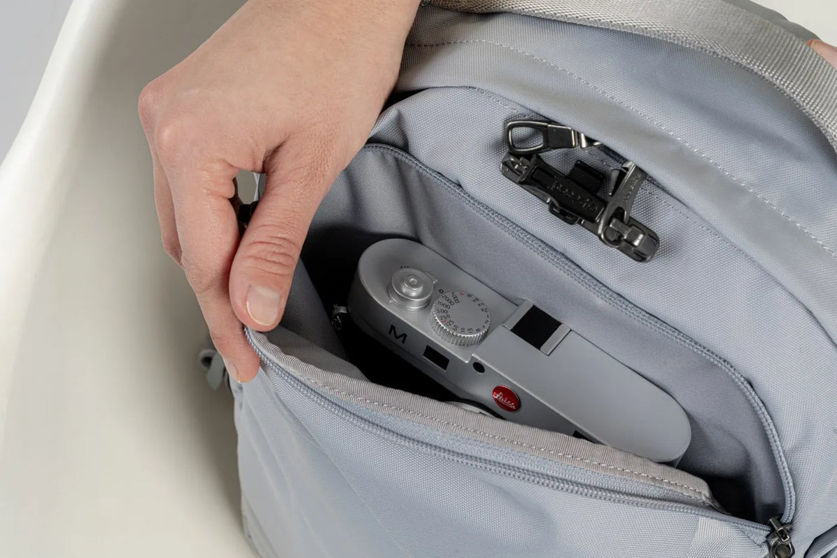 Pacsafe V City 20L Anti-Theft 16" Laptop Backpack in Digital Grey, a camera tucked into the padded pocket inside the bag
