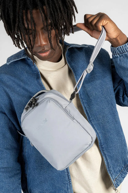 Pacsafe V Companion Anti-Theft Crossbody Bag in Digital Grey, worn on the chest over a denim jacket, the strap being adjusted