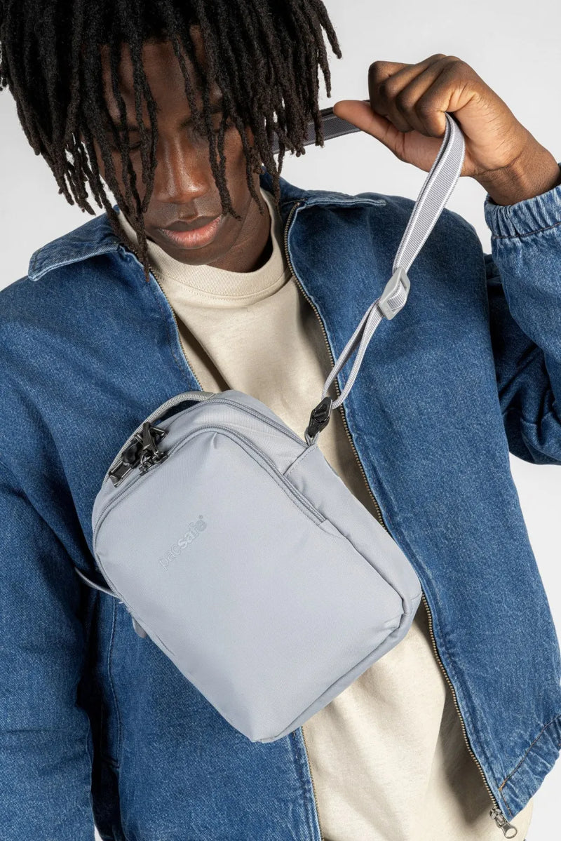 Pacsafe V Companion Anti-Theft Crossbody Bag in Digital Grey, worn on the chest over a denim jacket, the strap being adjusted