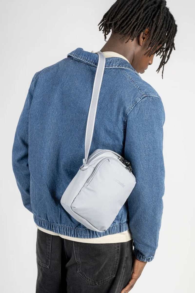Pacsafe V Companion Anti-Theft Crossbody Bag in Digital Grey, worn crossbody at the back over a denim jacket, seen from behind