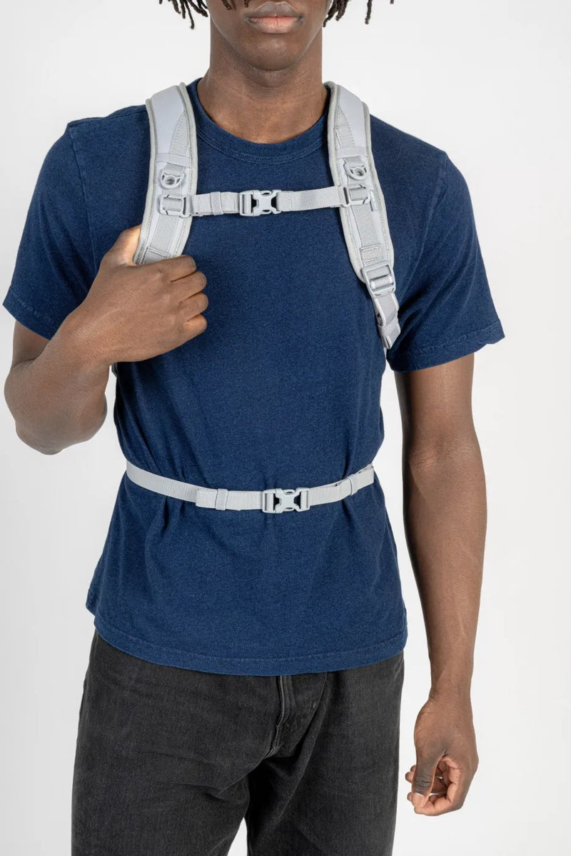 Pacsafe V Tech 12L Anti-Theft Backpack in Digital Grey, chest and waist straps clipped over a navy tee, seen from the front