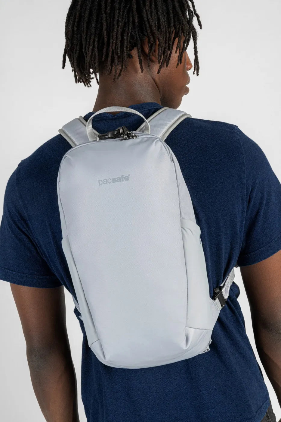 Pacsafe V Tech 12L Anti-Theft Backpack in Digital Grey, worn across the back over a navy tee, seen from behind