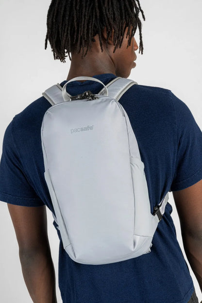 Pacsafe V Tech 12L Anti-Theft Backpack in Digital Grey, worn across the back over a navy tee, seen from behind